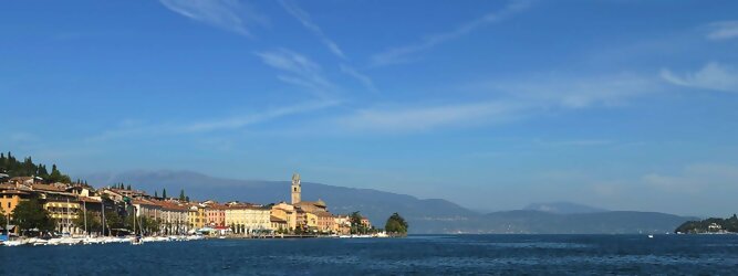 Trip Europa beliebte Urlaubsziele am Gardasee -  Mit einer Fläche von 370 km² ist der Gardasee der größte See Italiens. Es liegt am Fuße der Alpen und erstreckt sich über drei Staaten: Lombardei, Venetien und Trentino. Die maximale Tiefe des Sees beträgt 346 m, er hat eine längliche Form und sein nördliches Ende ist sehr schmal. Dort ist der See von den Bergen der Gruppo di Baldo umgeben. Du trittst aus deinem gemütlichen Hotelzimmer und es begrüßt dich die warme italienische Sonne. Du blickst auf den atemberaubenden Gardasee, der in zahlreichen Blautönen schimmert - von tiefem Dunkelblau bis zu funkelndem Türkis. Majestätische Berge umgeben dich, während die Brise sanft deine Haut streichelt und der Duft von blühenden Zitronenbäumen deine Nase kitzelt. Du schlenderst die malerischen, engen Gassen entlang, vorbei an farbenfrohen, blumengeschmückten Häusern. Vereinzelt unterbricht das fröhliche Lachen der Einheimischen die friedvolle Stille. Du fühlst dich wie in einem Traum, der nicht enden will. Jeder Schritt führt dich zu neuen Entdeckungen und Abenteuern. Du probierst die köstliche italienische Küche mit ihren frischen Zutaten und verführerischen Aromen. Die Sonne geht langsam unter und taucht den Himmel in ein leuchtendes Orange-rot - ein spektakulärer Anblick.